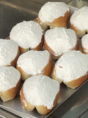 a platter filled with maritozzi: brioche stile buns sliced on the tip and filled with whipped cream