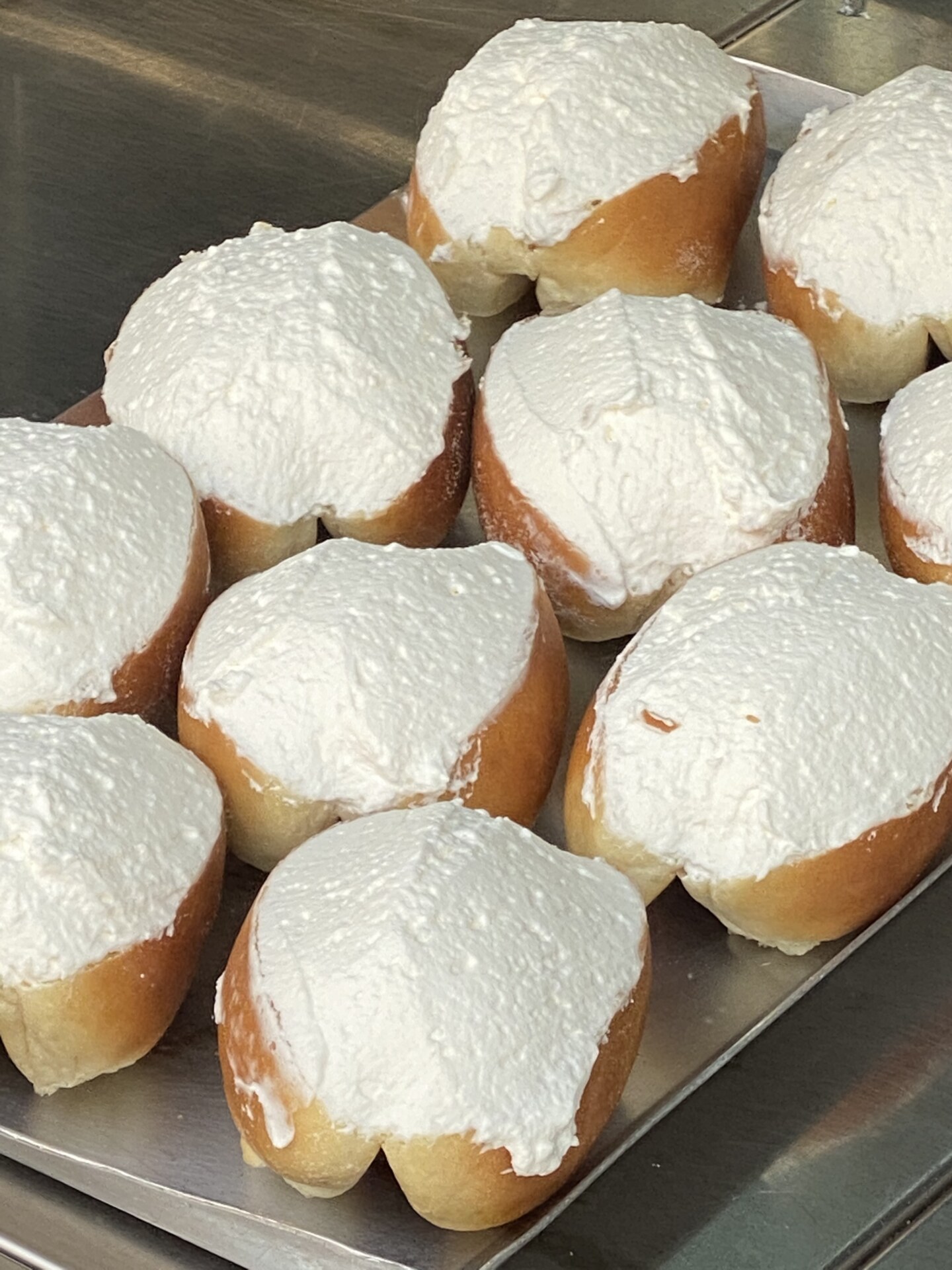 a platter filled with maritozzi: brioche stile buns sliced on the tip and filled with whipped cream