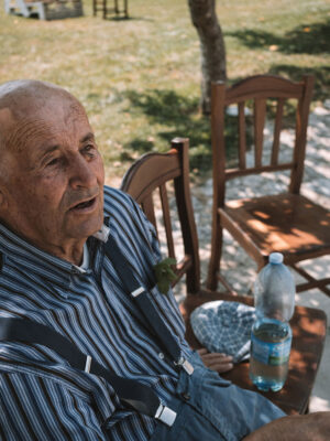 an old man sitting at a table in Calabria talking