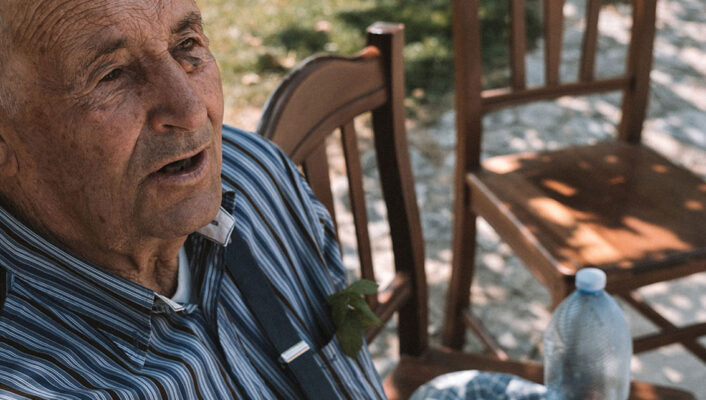 an old man sitting at a table in Calabria talking