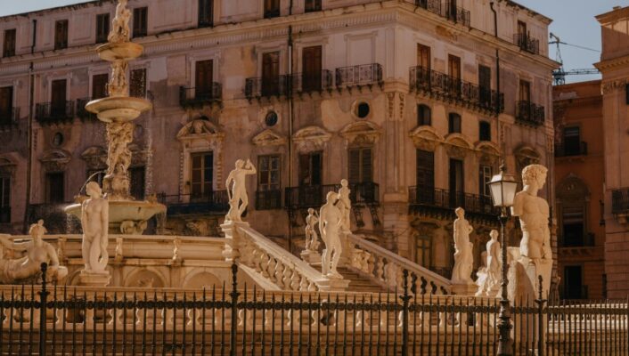 the white marble circular Fontana Pretoria adorned by statues in a piazza in Palermo