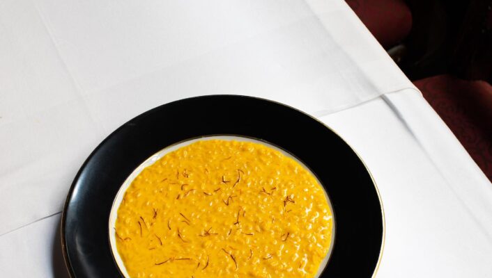 an image of bright yellow risotto alla milanese on a black plate from Da Giacomo
