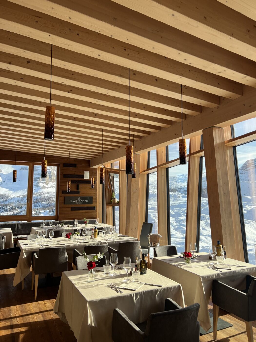 a dining room at Chalet Spinale with windows lvoerlooking the snowy peaks of the dolomites