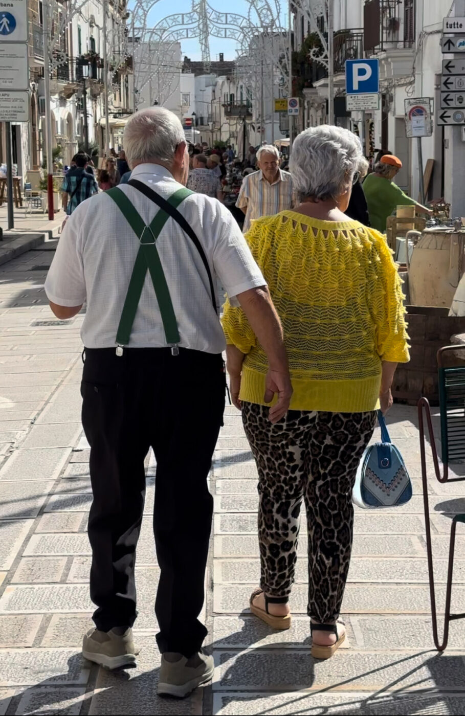 an image of an older Pugliese couple walking through the marketle walke