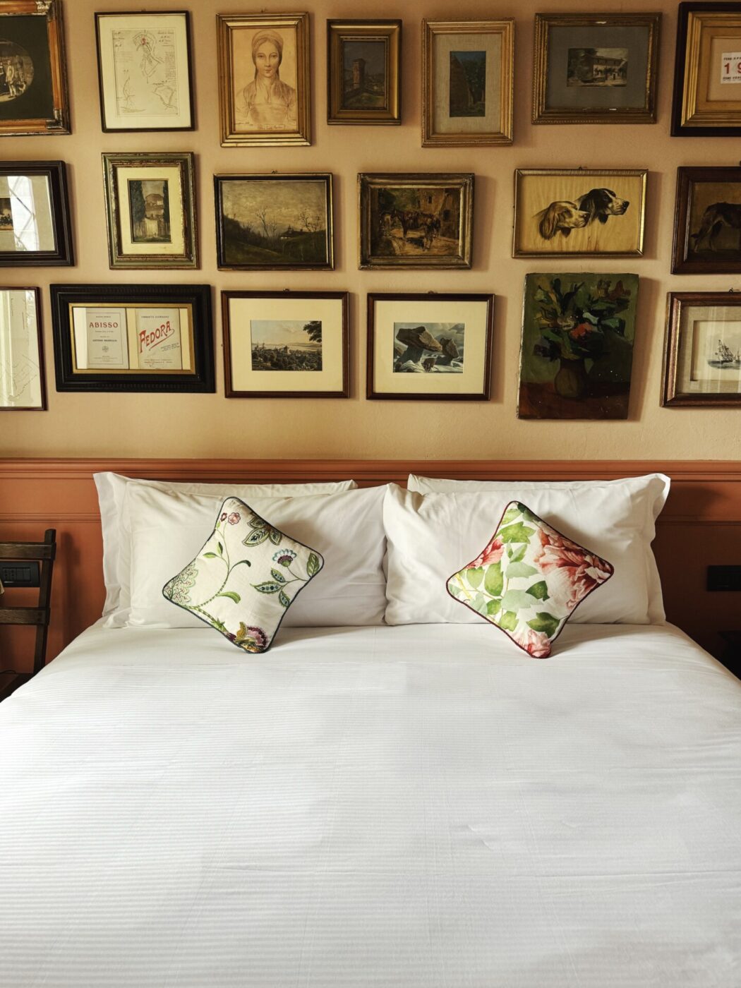 a bed at stella d'italia against a light yellow wall covered in framed photos