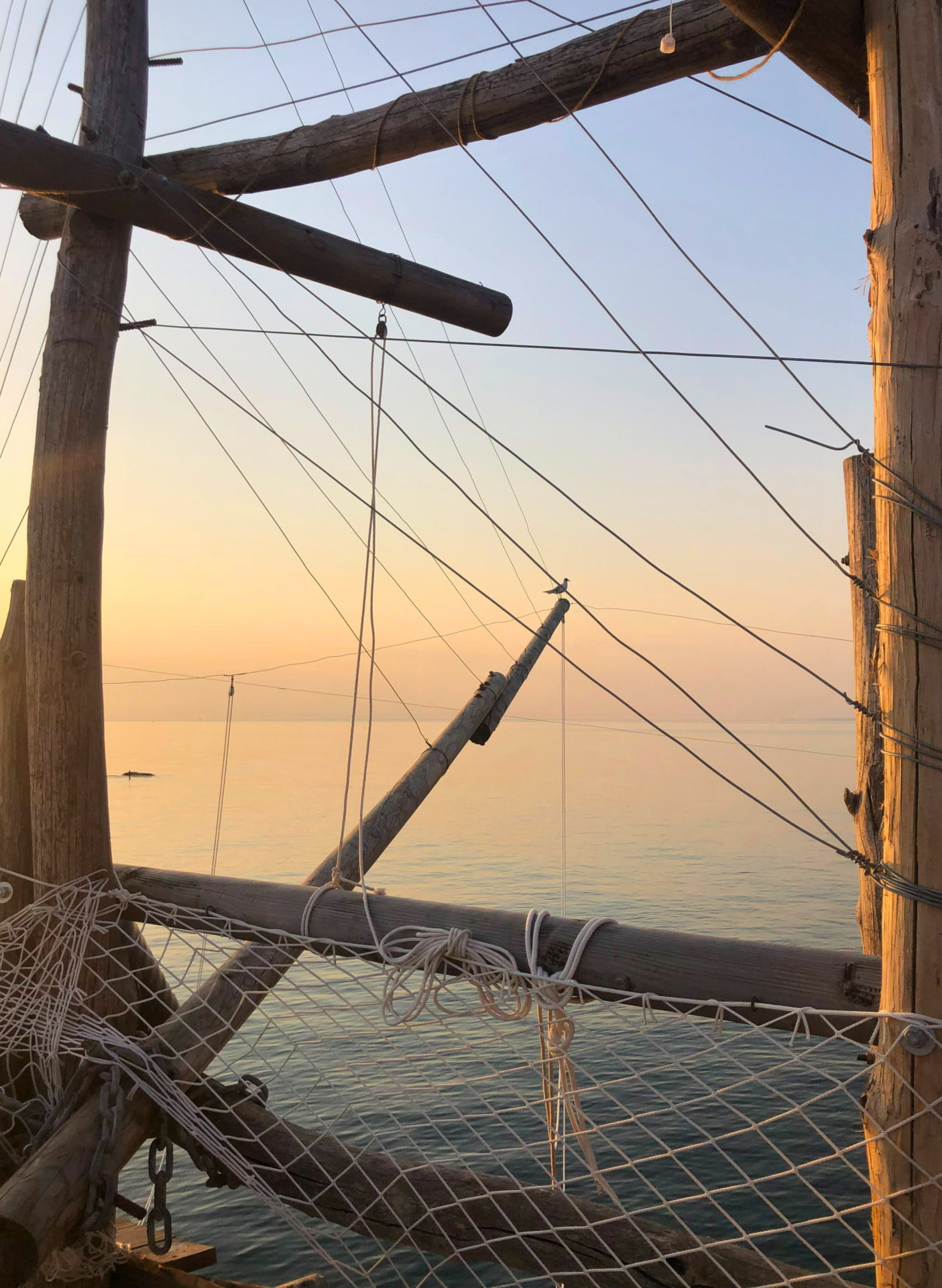 an image of antenna trabocco at sunset showing nets and poles extending out over the sea