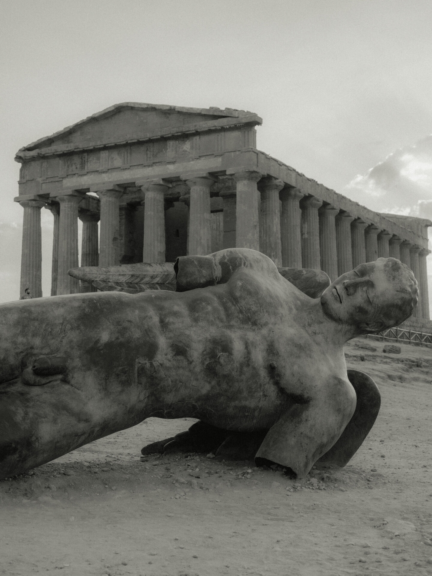an image of the Tempio della Concordia with a statue of a man laying in front of it