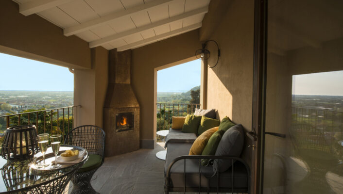 an image of a couch outside near a table with champagne at Locanda Al Colle and a lit furnace