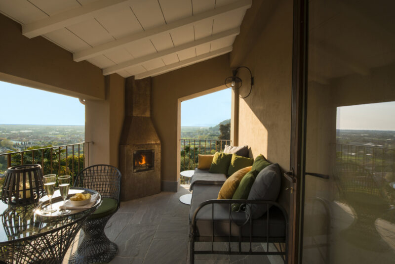 an image of a couch outside near a table with champagne at Locanda Al Colle and a lit furnace