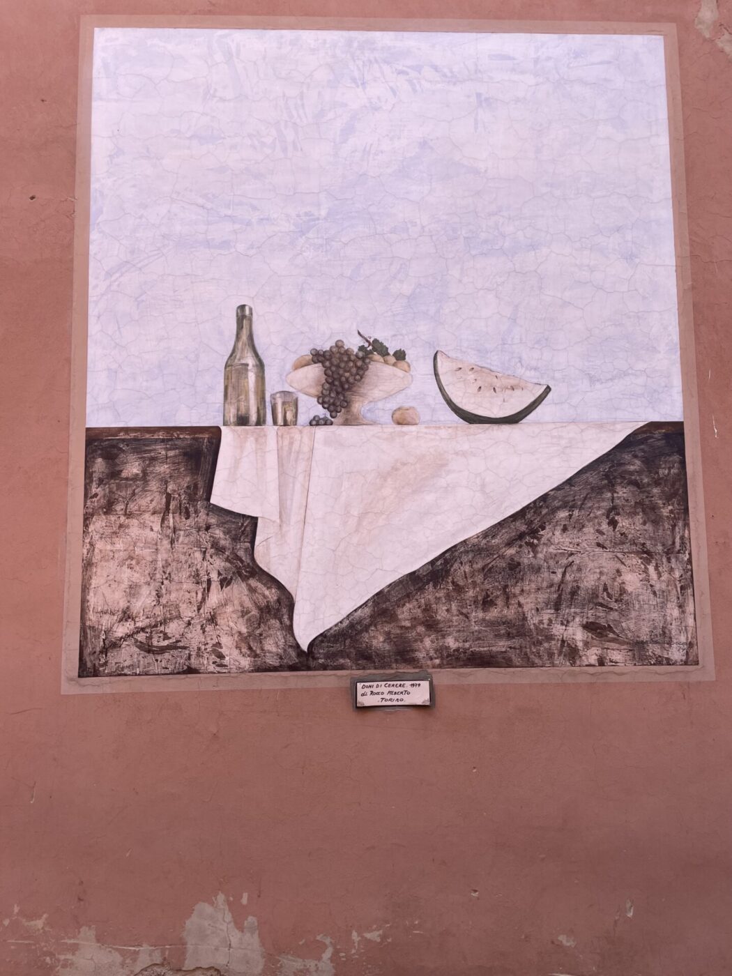 a still life painted on the wall in Dozza of wine cheese and grapes