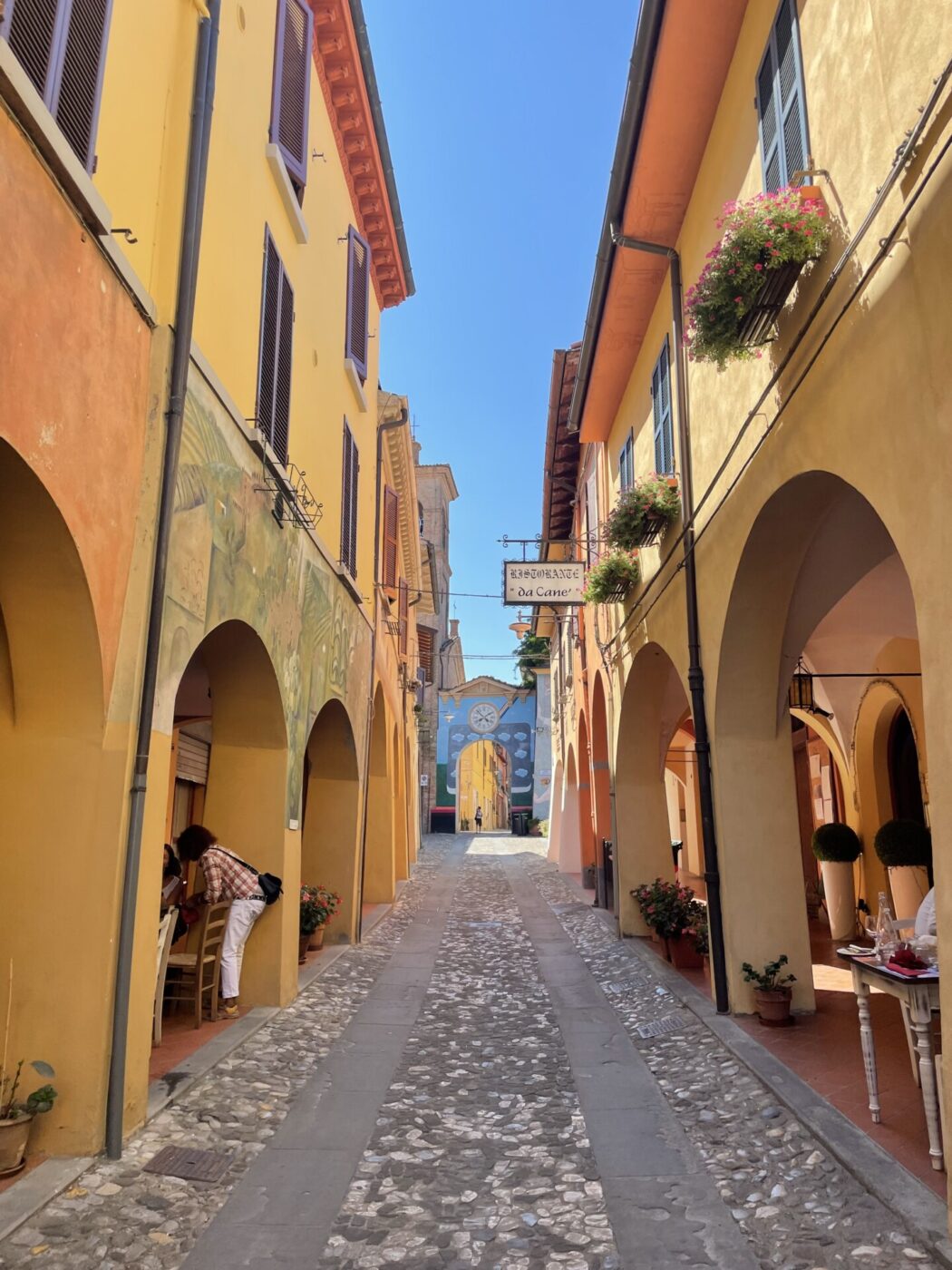 a street in Dozza with yellow and colorful, mural-covered walls