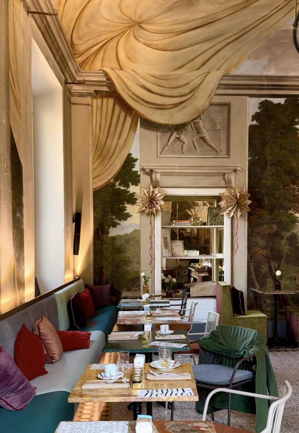 the interior breakfast area at stella d'italia with small tables along one long booth