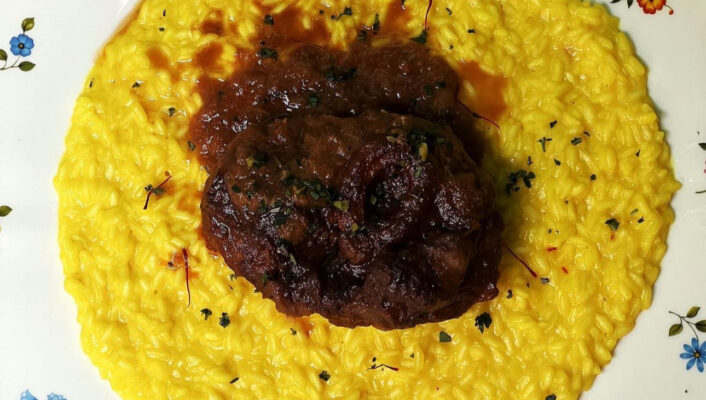 ossobucco on top of risotto alla milanese on a floral-patterned plate
