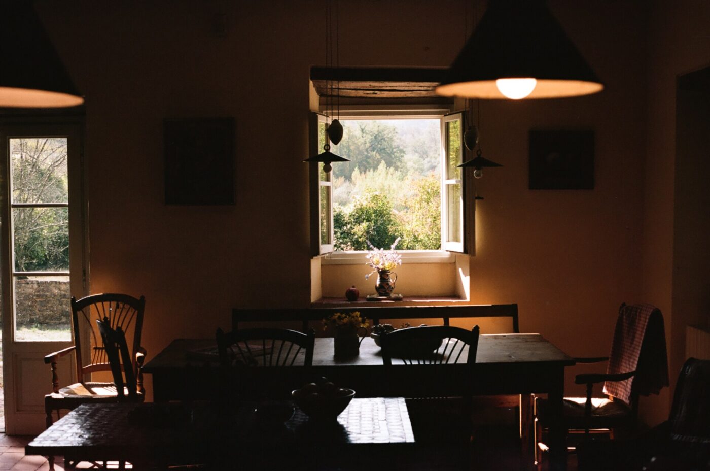 a dark lit image of a table inside a farmhouse looking out the open windows of Chianti