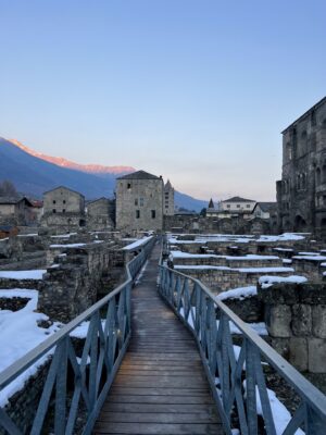 an image of some of the Roman ruins in Aosta covered in snow at sunset