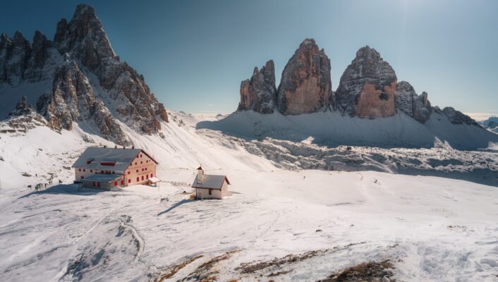 an image of the Dolomites covered in snow with a small rifugi in the center