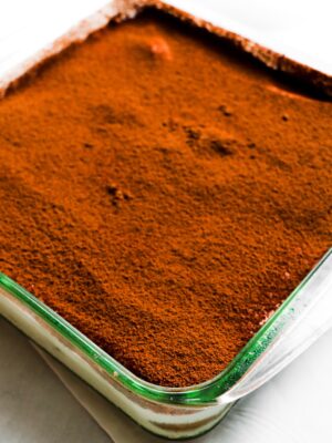 an image of a pyrex dish of tiramisu with cocoa powder all over the top