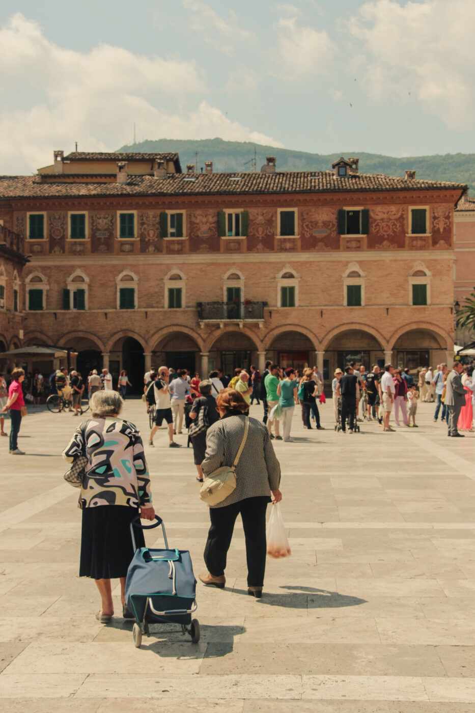 an image of people walking through a large piazza in Ascoli Marche
