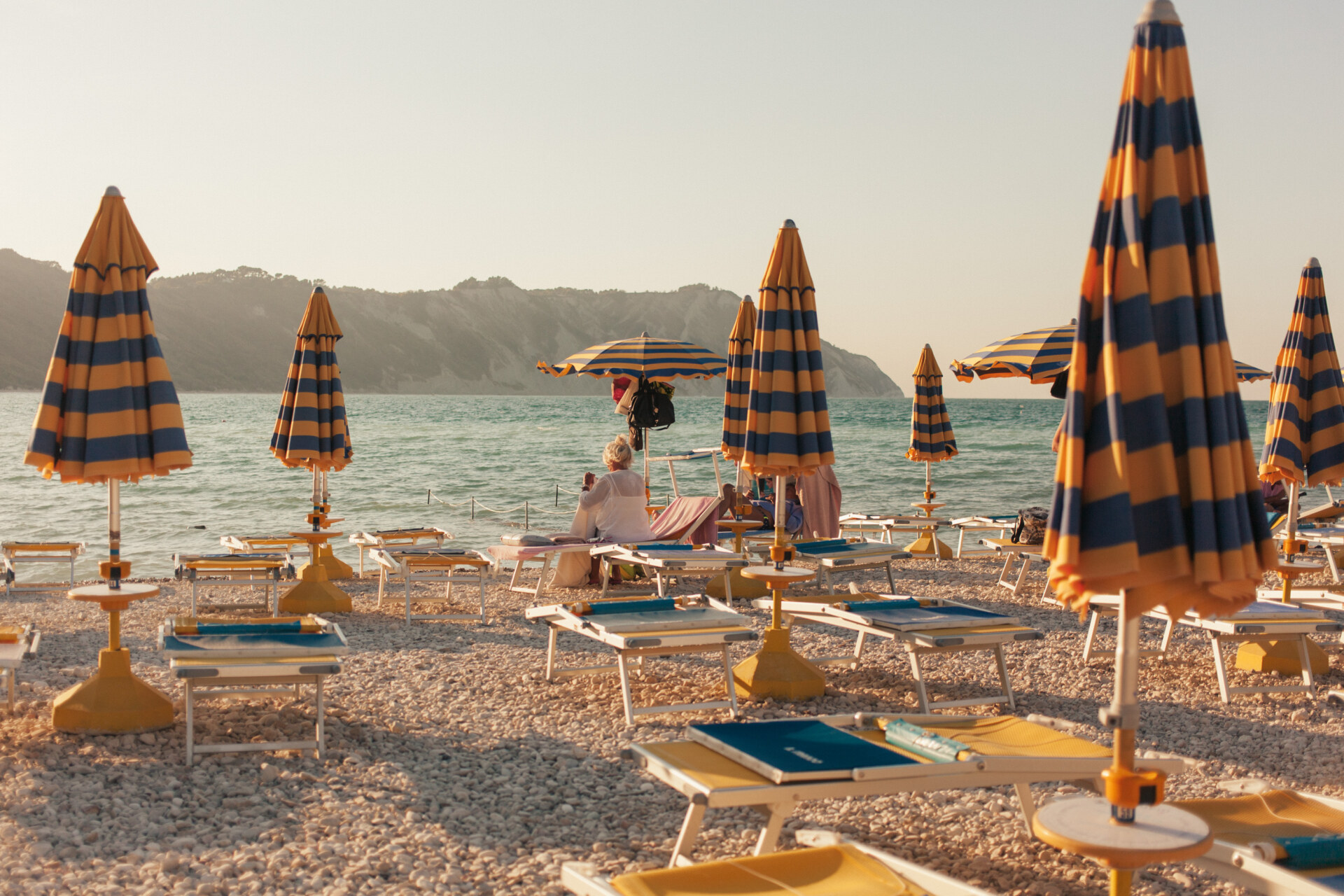 an image of blue and yellow umbrellas on the beach in Marche