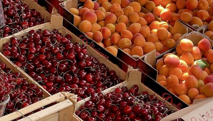 an image of boxes of peaches and cherries at a fruttivendolo