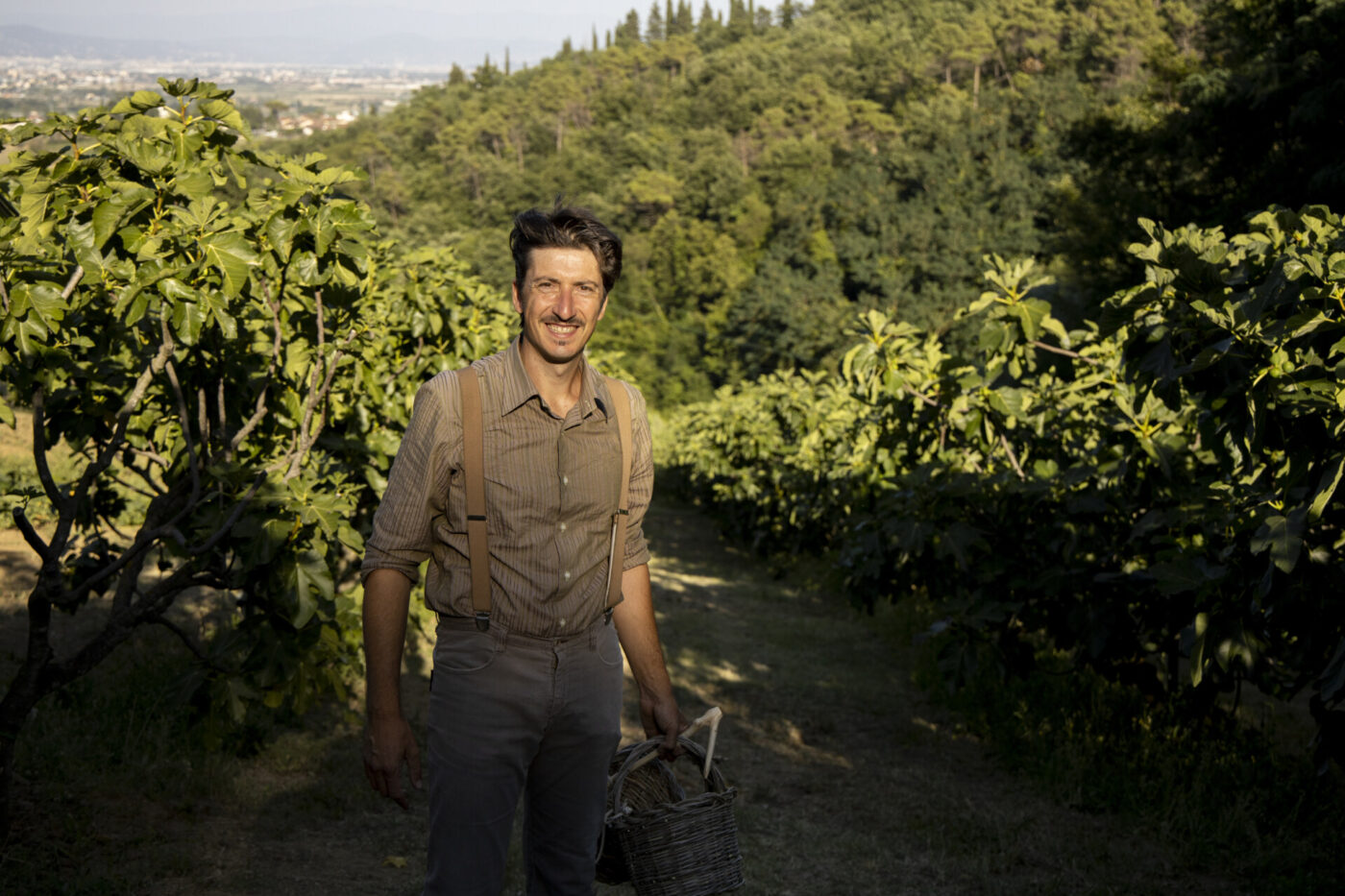 Siro Petracchi smiling and standing among his fig trees