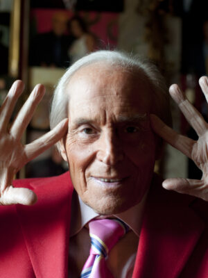 an image of Cesare Chiti (Mago Badoglio) up close holding his hands up to his ears