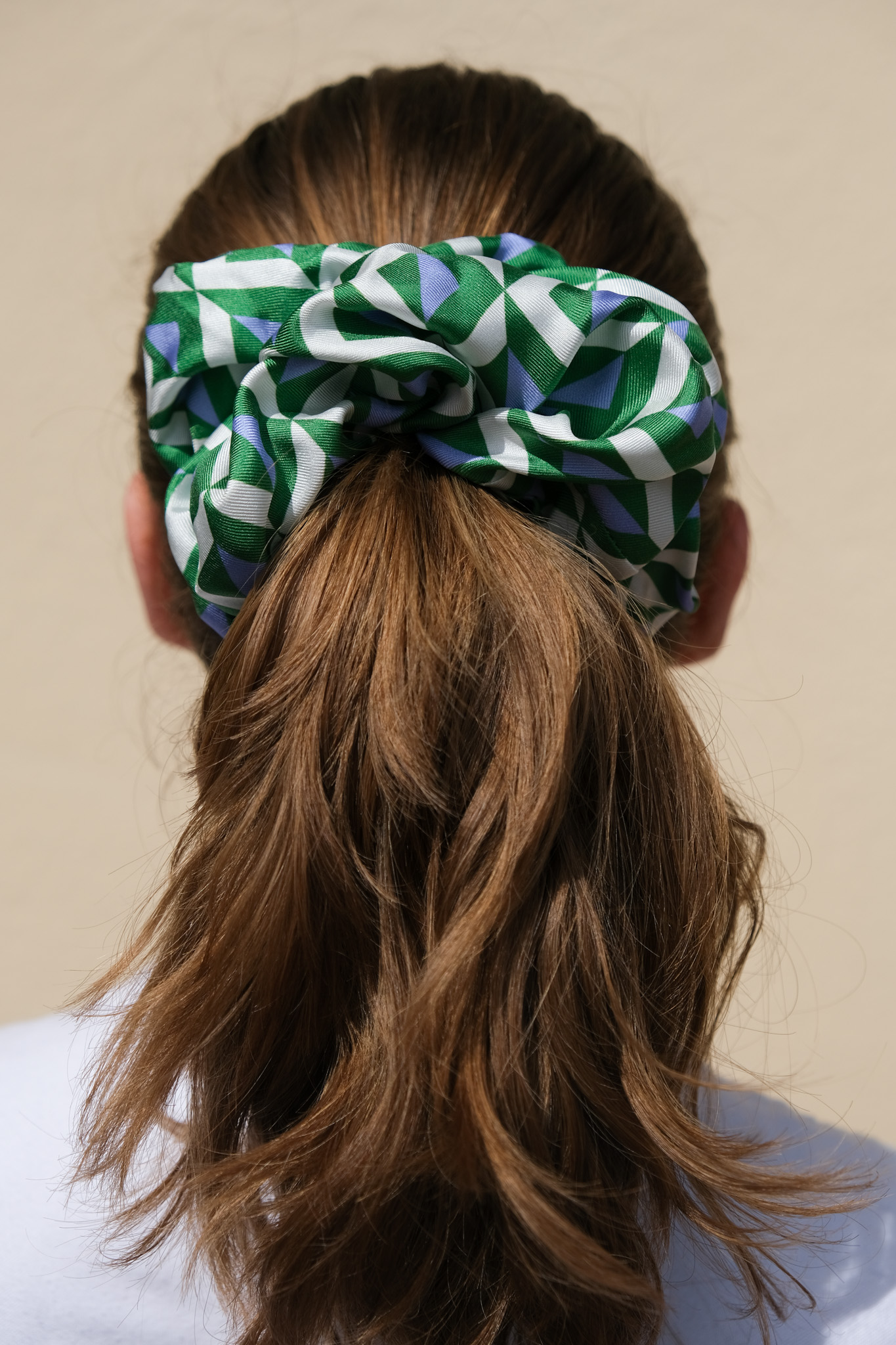 a woman from the back with her hair in a ponytail with a blue and green geometric scrunchie