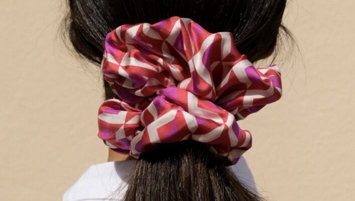 A woman from the back with her dark brown hair in a pink and purple scrunchie