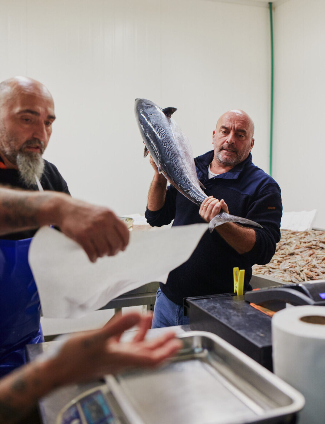 a man lifting a giant fish to place on a scale at the milan fish market