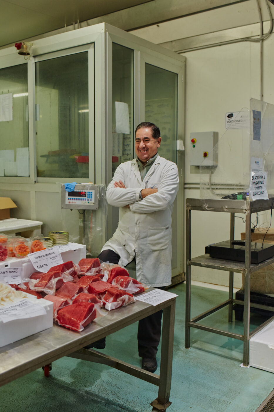 a fishmonger standing next to his table of fresh fish at the milan fish market