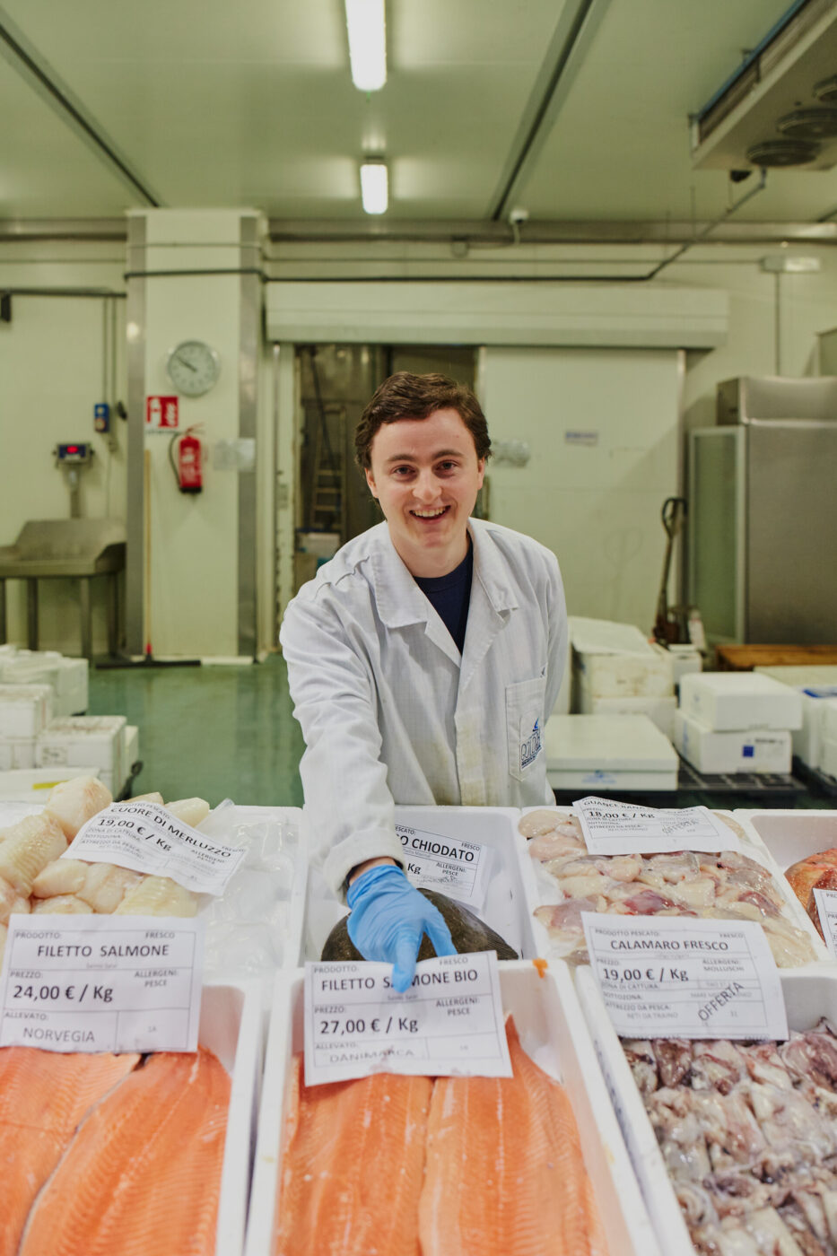 a fishmonger at the milan fish market pointing to his filets of salmon