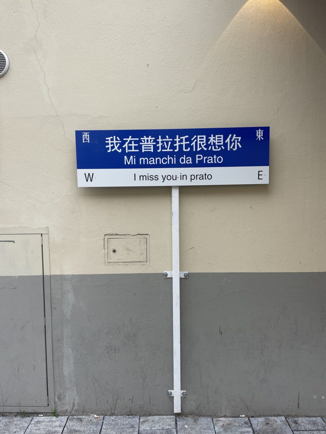 a sign in prato reading "I miss you in prato" in english, italian, and mandarin