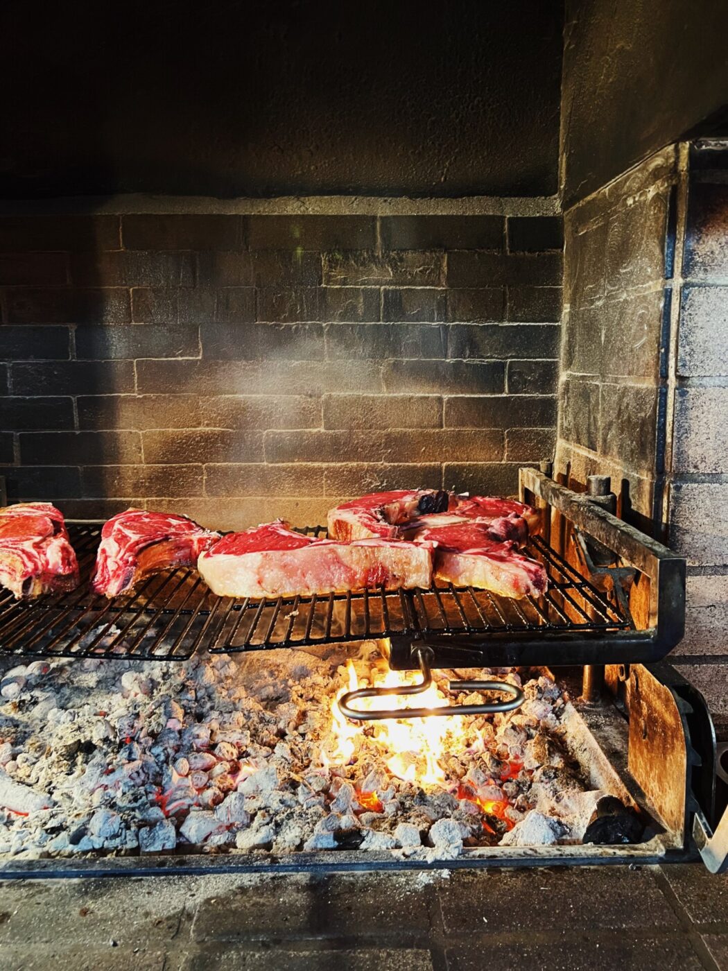 an image of bistecca fiorentina grilling over a fire
