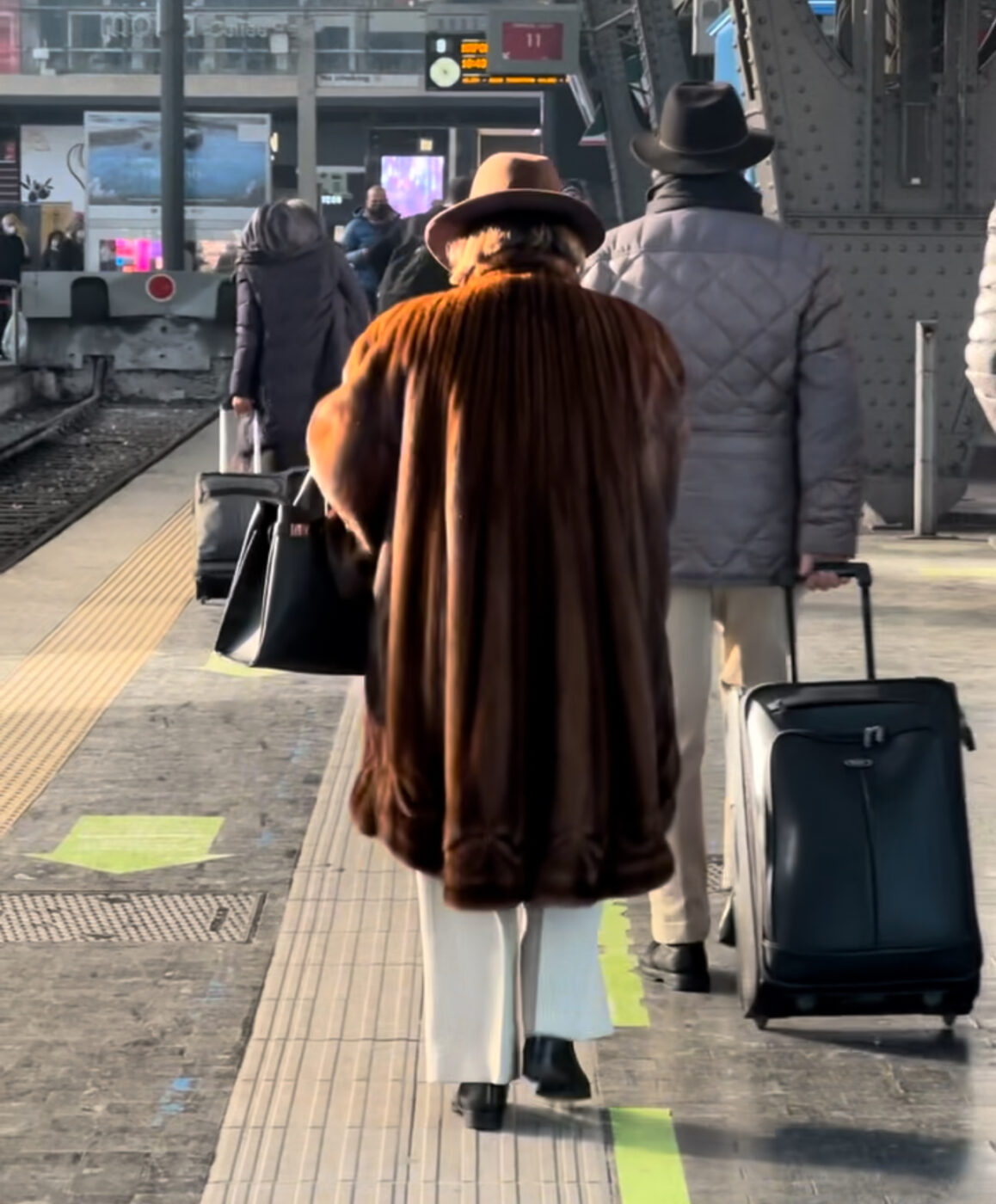 The back of a sciura walking in a train station