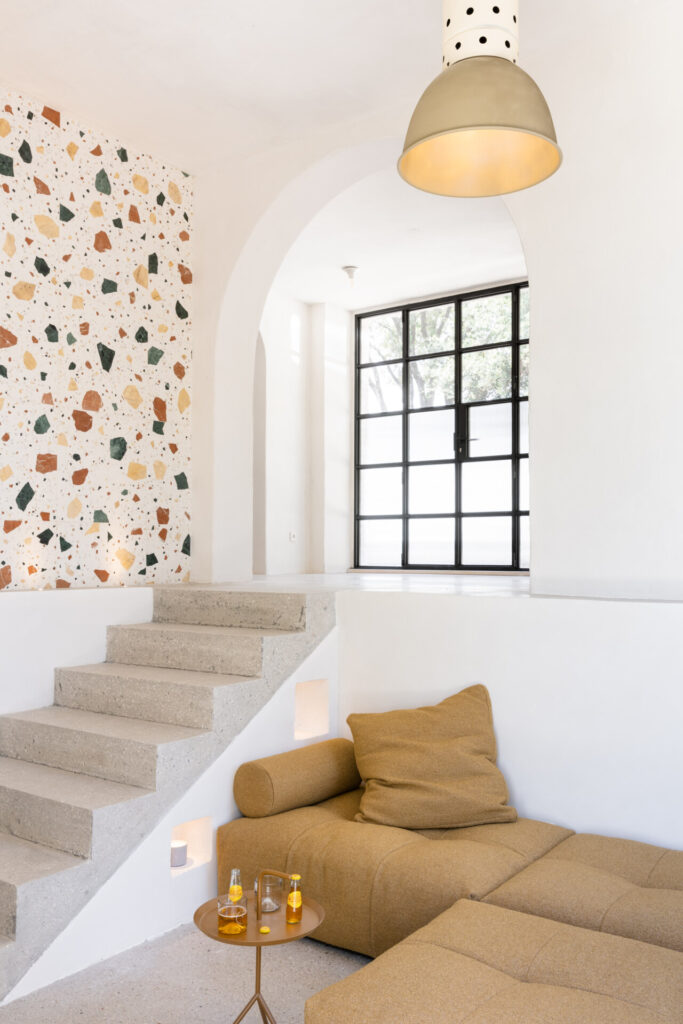 the brightly lit living room at La Casetta with a L couch next to stairs leading up to the terrace