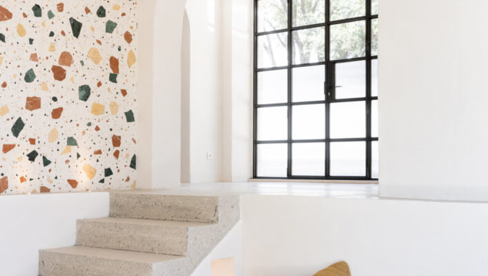 the brightly lit living room at La Casetta with a L couch next to stairs leading up to the terrace