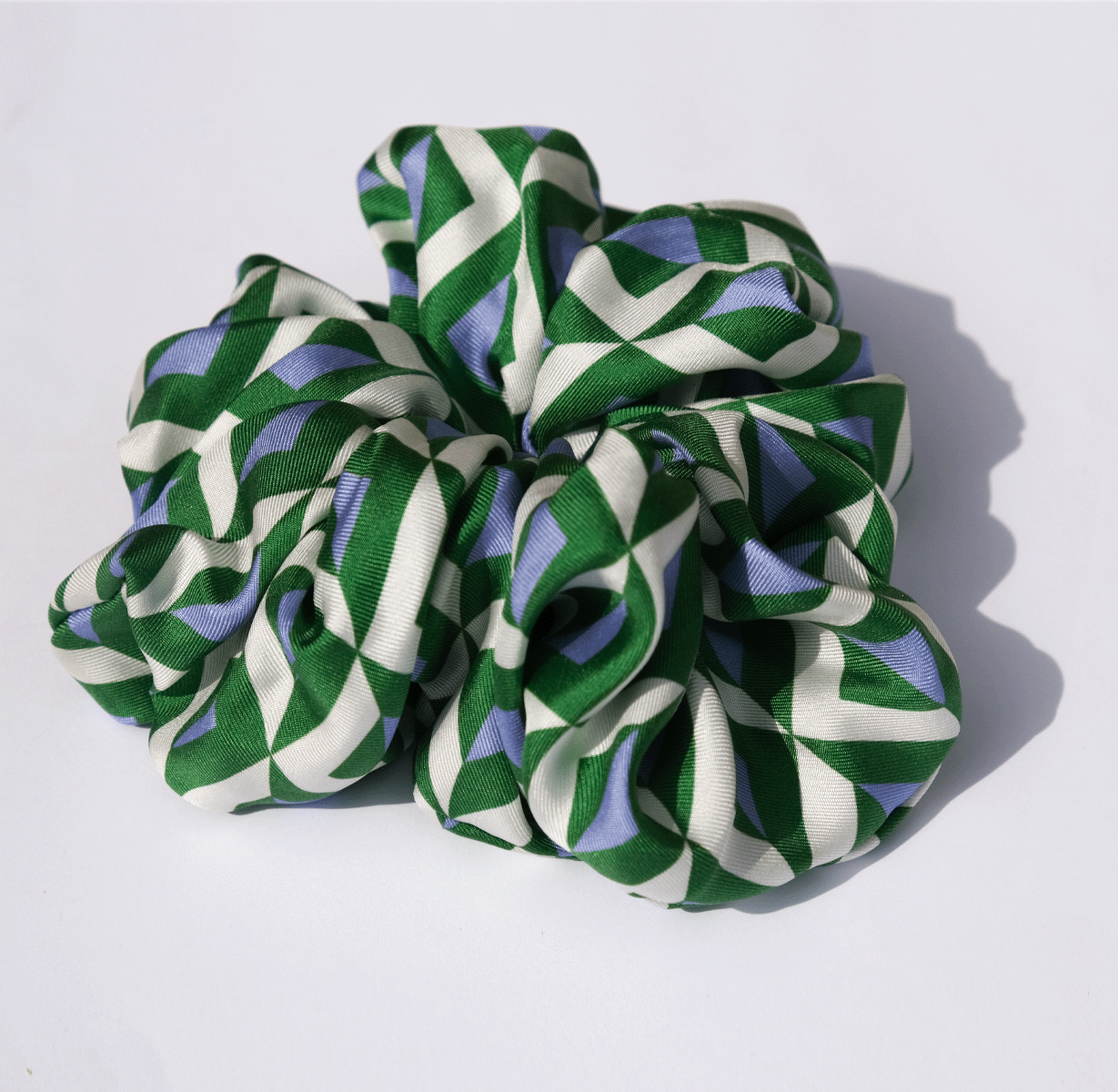 A close up of a scrunchie for your hair with a green and blue geometric pattern