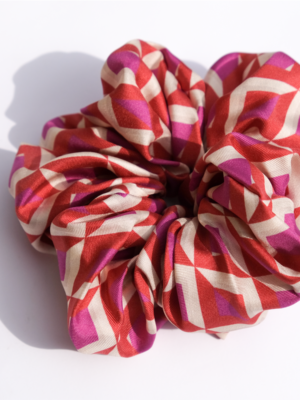 A close up of a scrunchie for your hair with a pink and purple geometric pattern