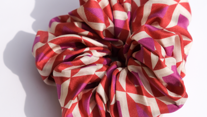 A close up of a scrunchie for your hair with a pink and purple geometric pattern