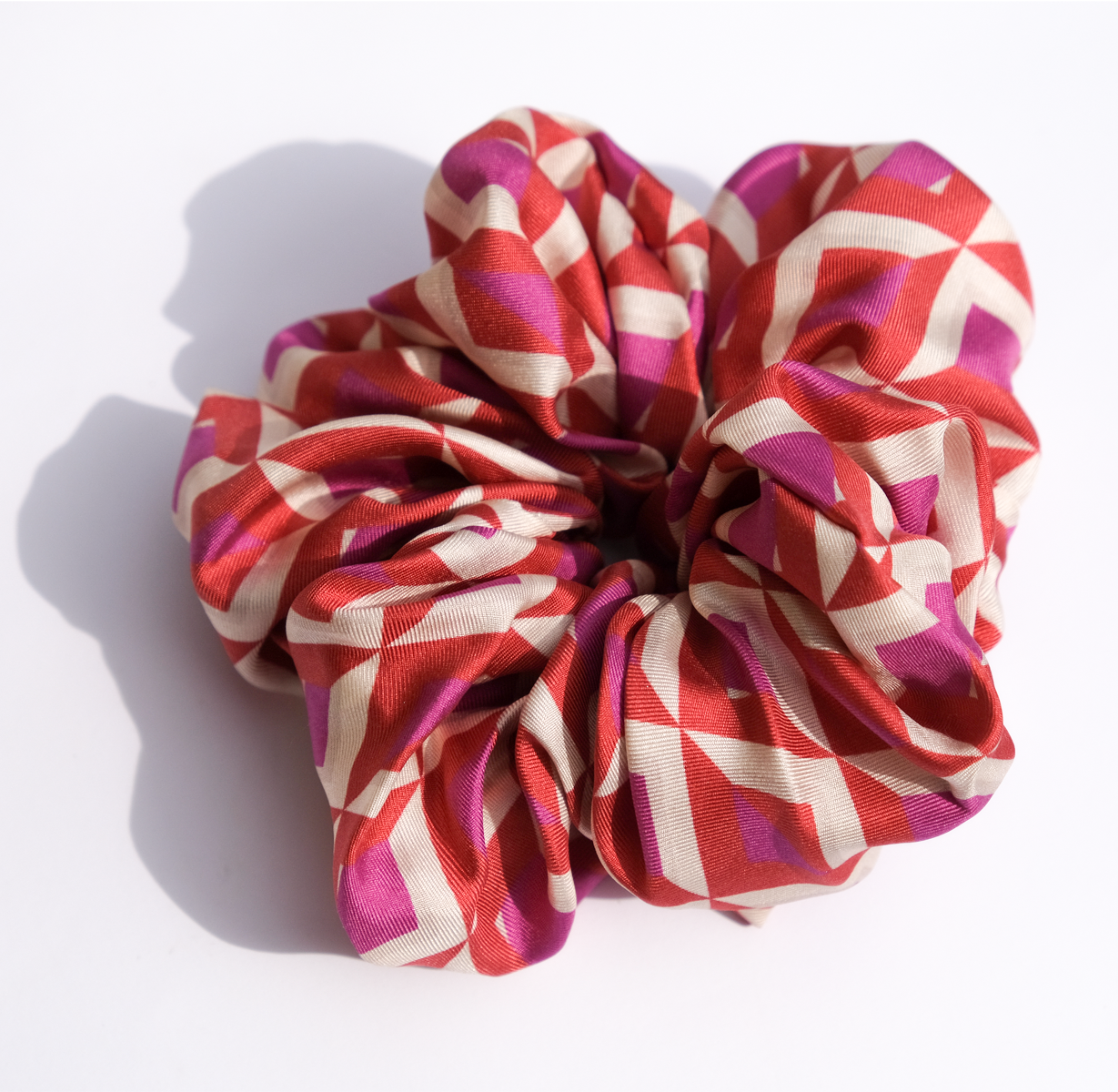 A close up of a scrunchie for your hair with a pink and purple geometric pattern
