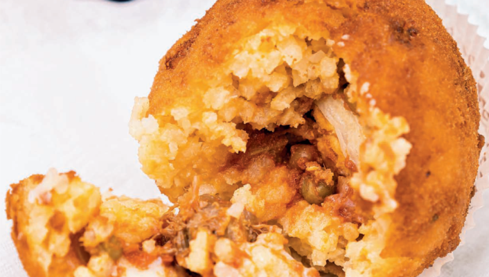 an arancine opened up with meat and cheese inside.