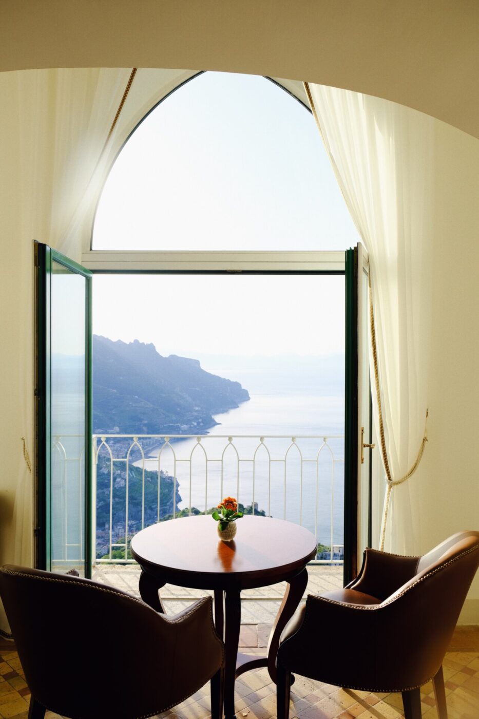 an image from inside the bar of a table against open doors onto the terrace overlooking the sea at Belmond Caruso