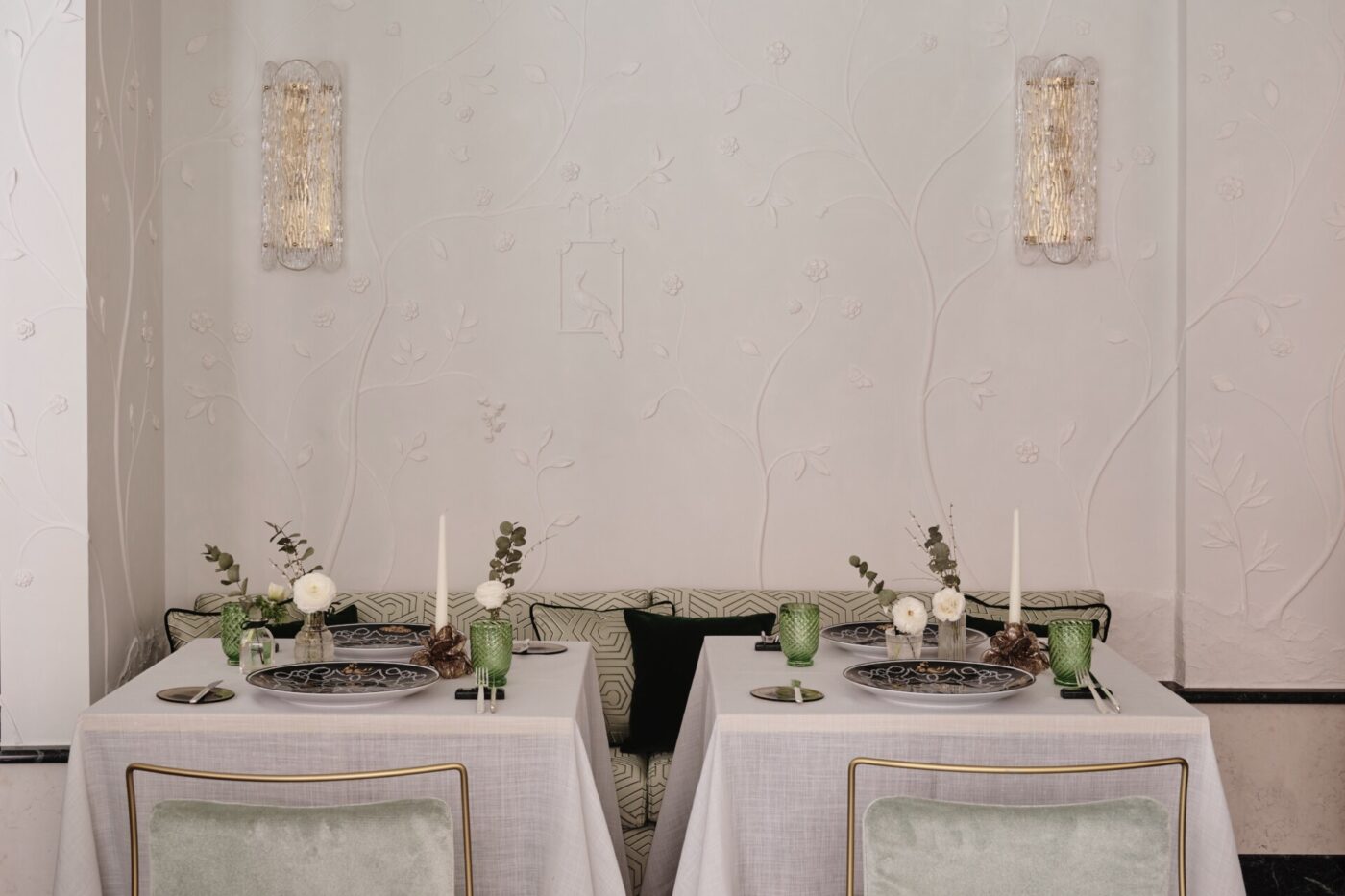 two small tables at Violino d'Oro against a patterned and textured white wall