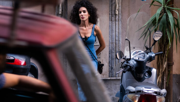 an image of a southern Italian woman in a blue tank top underneath an altar in Naples