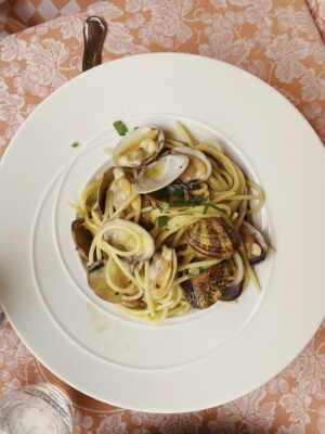 A dish of spaghetti alle vongole on a pink tablecloth