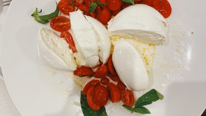 Caprese salad, sliced cherry tomatoes, mozzarella di bufala and basil leaves