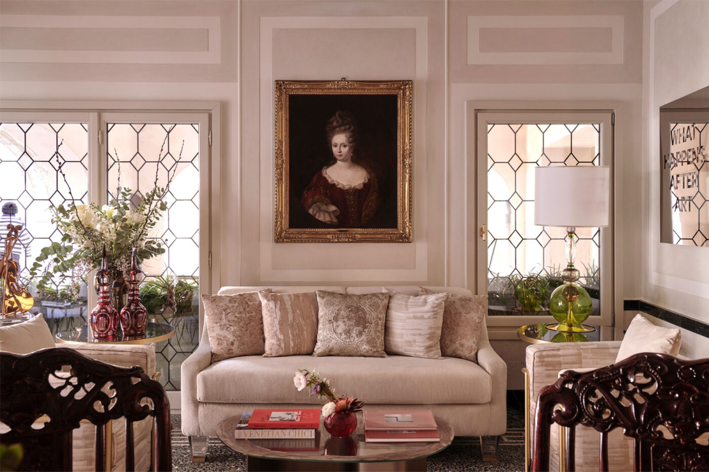 an image of a couch framed by two windows and a large photo of a woman at violino d'oro