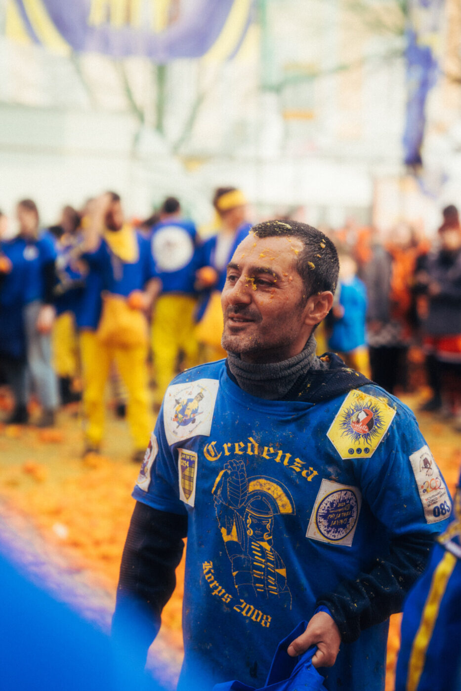 a close up of a man on the blue team at Ivrea with his face covered with orange pupl