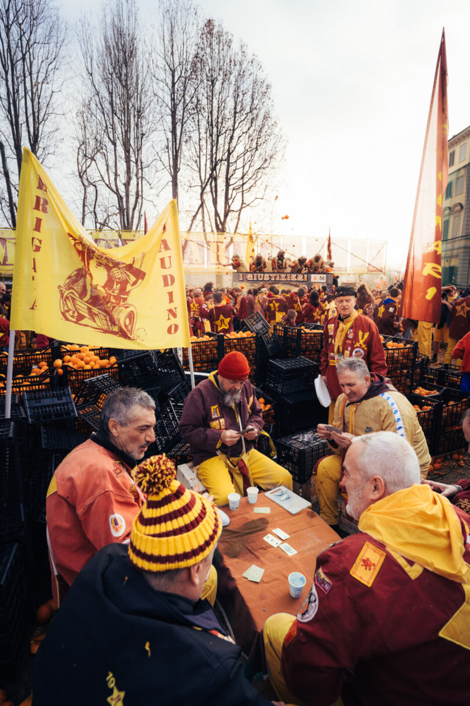 men sitting around a table playing cards amidst orange crates