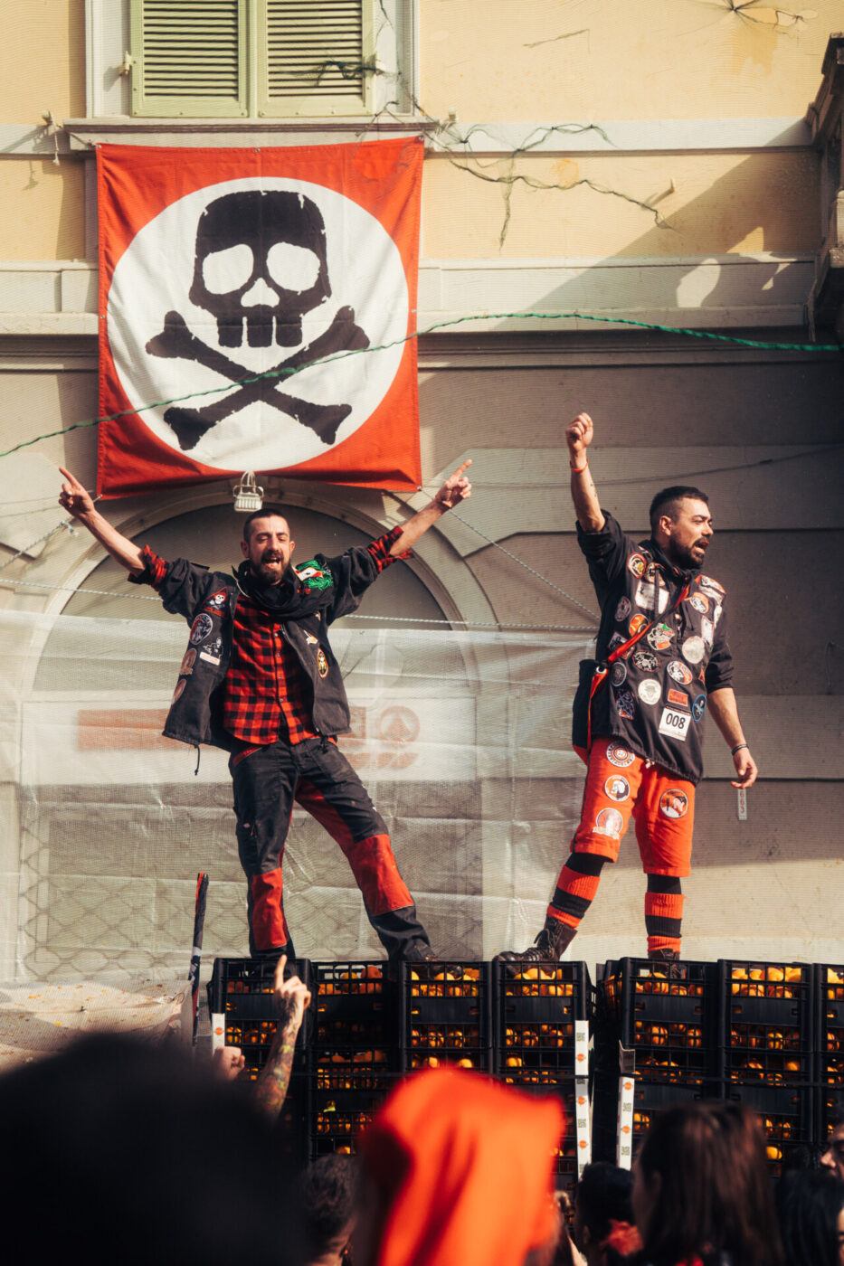 two young boys on team death standing atop crates of oranges with their hands raised and cheering